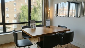A modern room with a large window, a wooden table, and black chairs. - Still Life Warren Street (London)