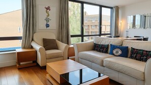 A modern living room with a sofa, armchair, and a glass coffee table. - Still Life Warren Street (London)