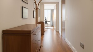 A hallway with wooden flooring, a built-in wooden bench, and a door leading to another room. - Still Life Warren Street (London)