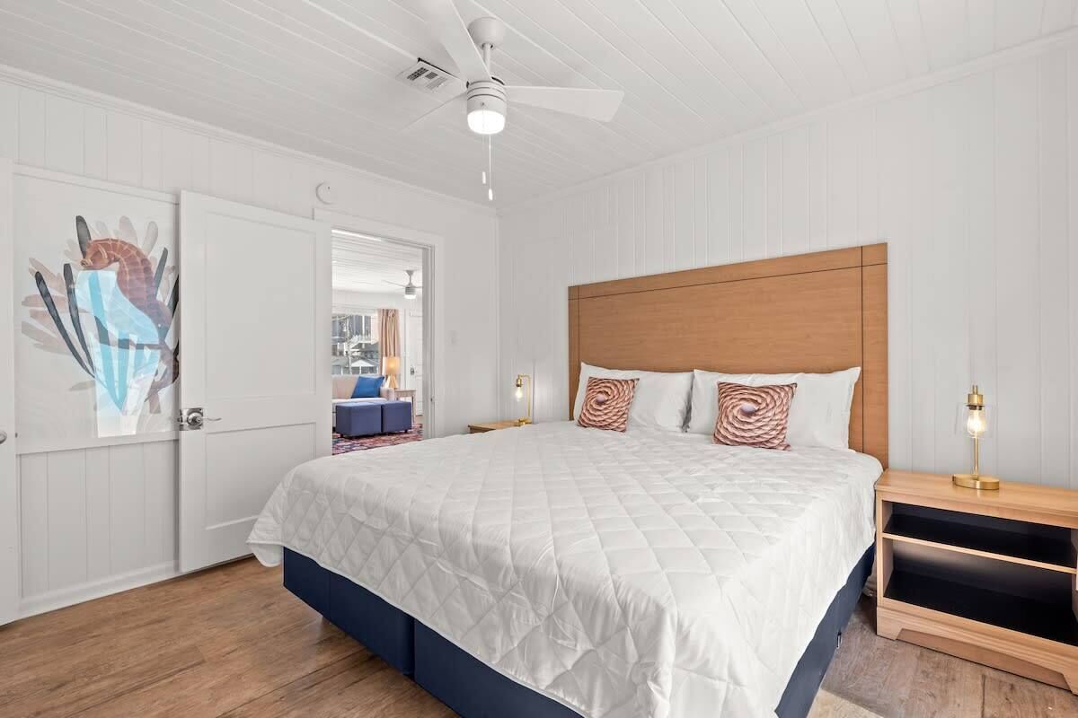 Una camera da letto con un letto grande, una testiera in legno, una ventola a soffitto e un comodino con una lampada.