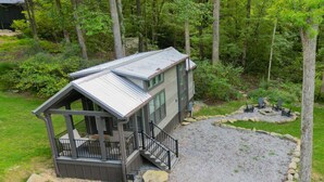 Eine Hütte mit einer Terrasse, einer Schotterauffahrt und umliegendem Waldgebiet.