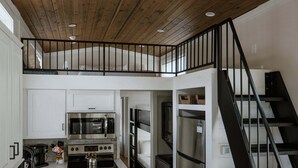 Una cocina moderna con armarios blancos, un horno de acero inoxidable y una escalera negra.
