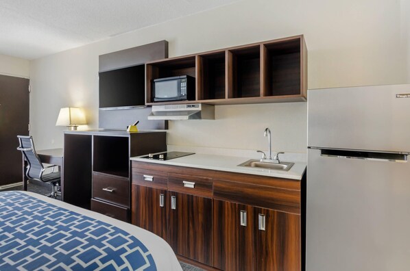 A hotel room with a bed, a desk, a microwave, a refrigerator, and a sink. - Suburban Studios Verona - Staunton North (Verona)