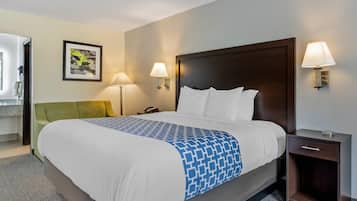 Een hotelkamer met een groot bed, twee bedlampen, een nachtkastje en een ingelijst schilderij aan de muur.