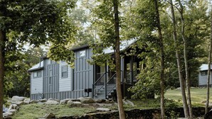 A cabin with a stone foundation, wooden steps, and a metal railing. - Willow Cabin by Creekside Hideaway (Gatlinburg)