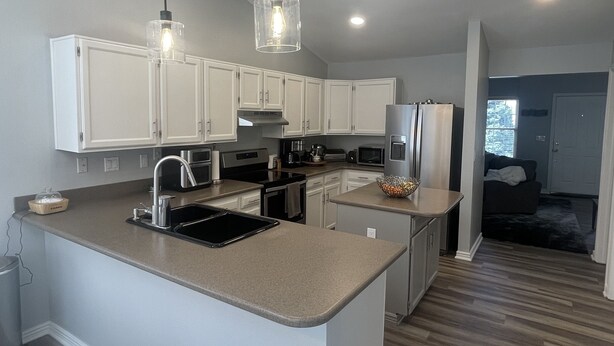 Una cocina moderna con armarios blancos, una isla grande e iluminación colgante.