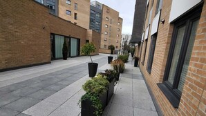 A corridor with potted plants, brick buildings, and a clear sky. - Captivating 2-bed Apartment in Glasgow (Glasgow)