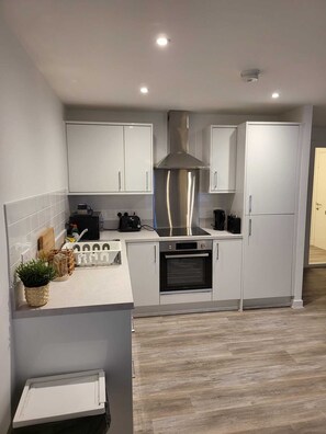 A modern kitchen with white cabinets, a stainless steel range hood, an oven, and a built-in microwave. - Captivating 2-bed Apartment in Glasgow (Glasgow)