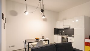 A modern kitchen with white cabinets, a dining table with chairs, and a black sofa in the foreground. - Guelfa 14 - Two Bedroom Apartment, Sleeps 4 (Firenze)