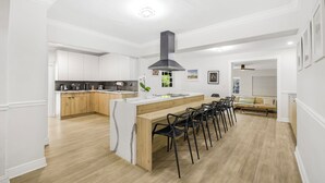 Uma cozinha moderna com armários brancos, uma ilha de madeira e um exaustor preto.
