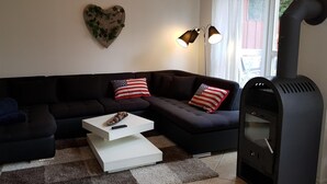 A living room with a dark-colored sofa, a white coffee table, and a black wood-burning stove. - FH Falster XXL im Schlosspark Bad Saarow, 178m², 8+4 Pers, Sauna,Whirlpool,Kamin (Bad Saarow)