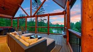 Une terrasse en bois, meublée de mobilier en osier, avec vue sur une zone boisée.