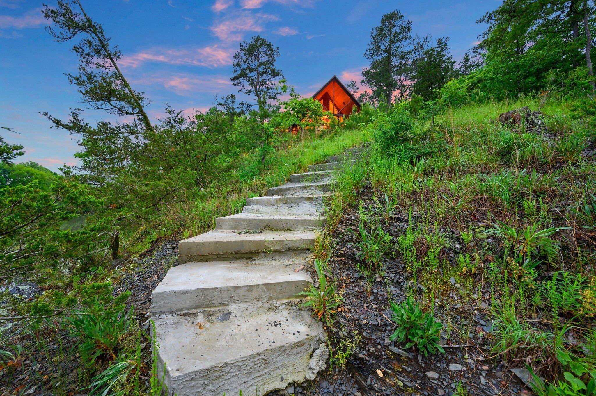 Un escalier en pierre mène à un chalet en bois situé dans une zone boisée.