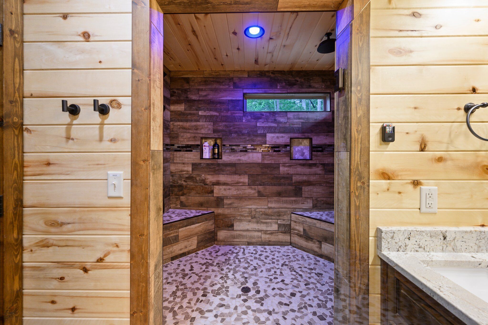 Ein Holzblock-Interieur mit Mosaikboden, Holzwänden und einem kleinen Fenster.