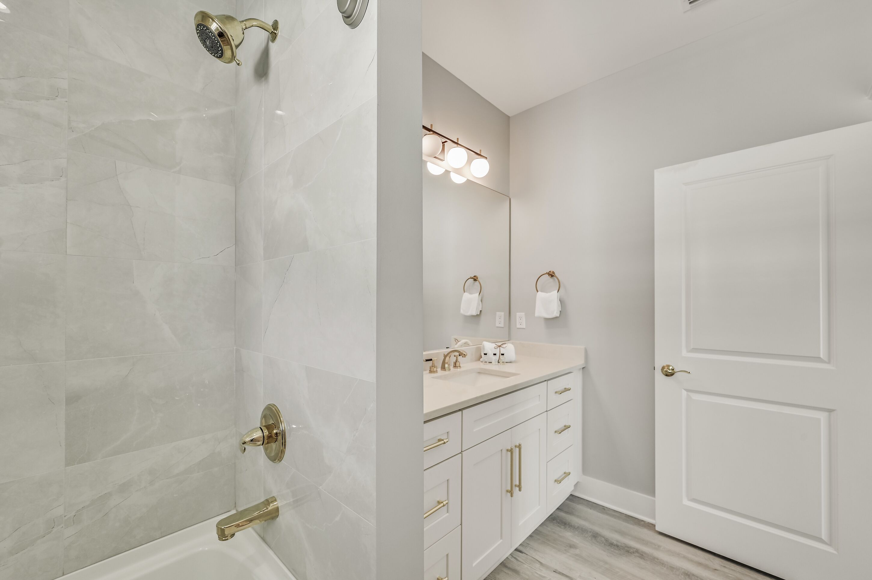 A bathroom with a shower, a sink with a mirror, and a door.