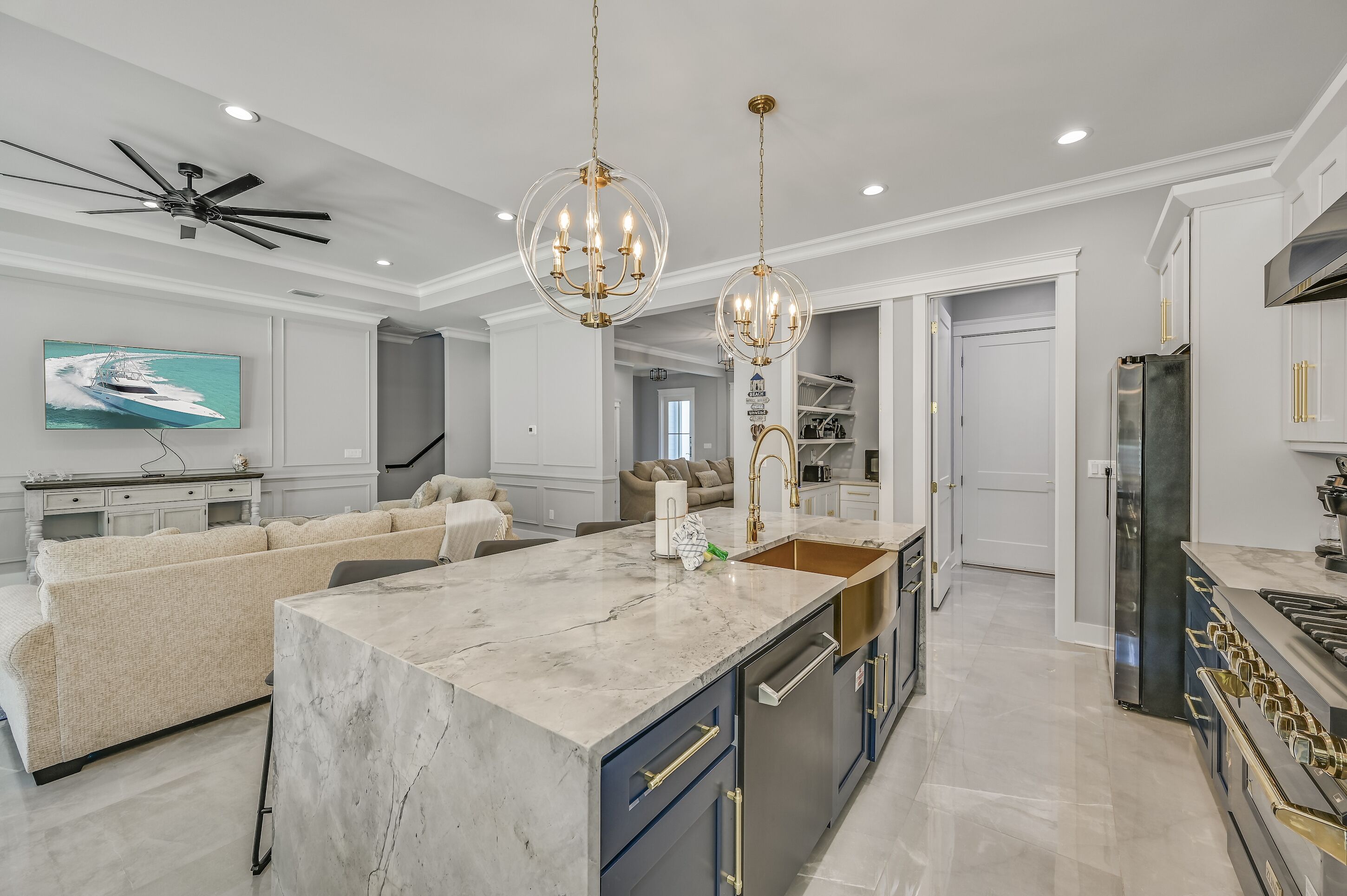 A spacious kitchen with a marble island, modern appliances, and pendant lighting.