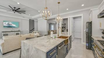 A spacious kitchen with a marble island, modern appliances, and pendant lighting.