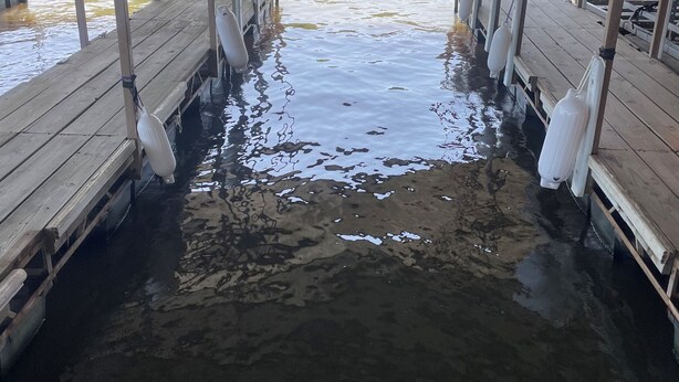 A wooden pier with benches and a covered area, extending over a body of water.