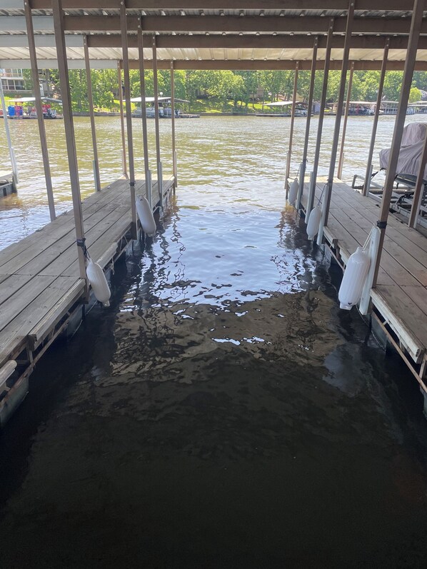 Un muelle de madera con bancos y un área techada, que se extiende sobre una masa de agua.