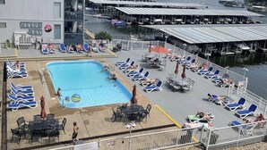A rooftop pool area with lounge chairs, a swimming pool, and a view of the marina.