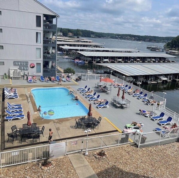 Un área de piscina en la azotea con sillones de descanso, una piscina y vistas al puerto deportivo.
