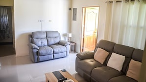 A living room with a grey sofa, a brown sofa, a wooden coffee table, and a lamp. - Twin Peak Cottage (Ocho Rios)