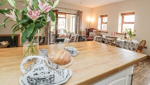 Ein gemütlicher Essbereich mit einem Holztisch, einer Blumenvase und einem Brot.