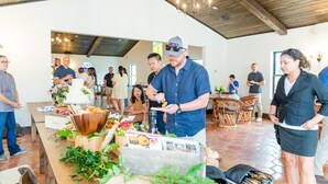A dining area with wooden tables and chairs, a buffet setup with various food items, and a chandelier hanging from the ceiling. - La Palmilla Texas (Glen Rose)