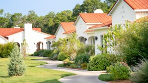 A row of white buildings with red roofs and a well-maintained garden. - La Palmilla Texas (Glen Rose)
