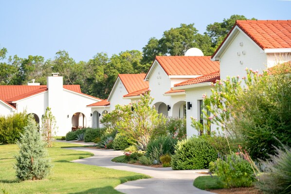A row of white buildings with red roofs and a well-maintained garden.