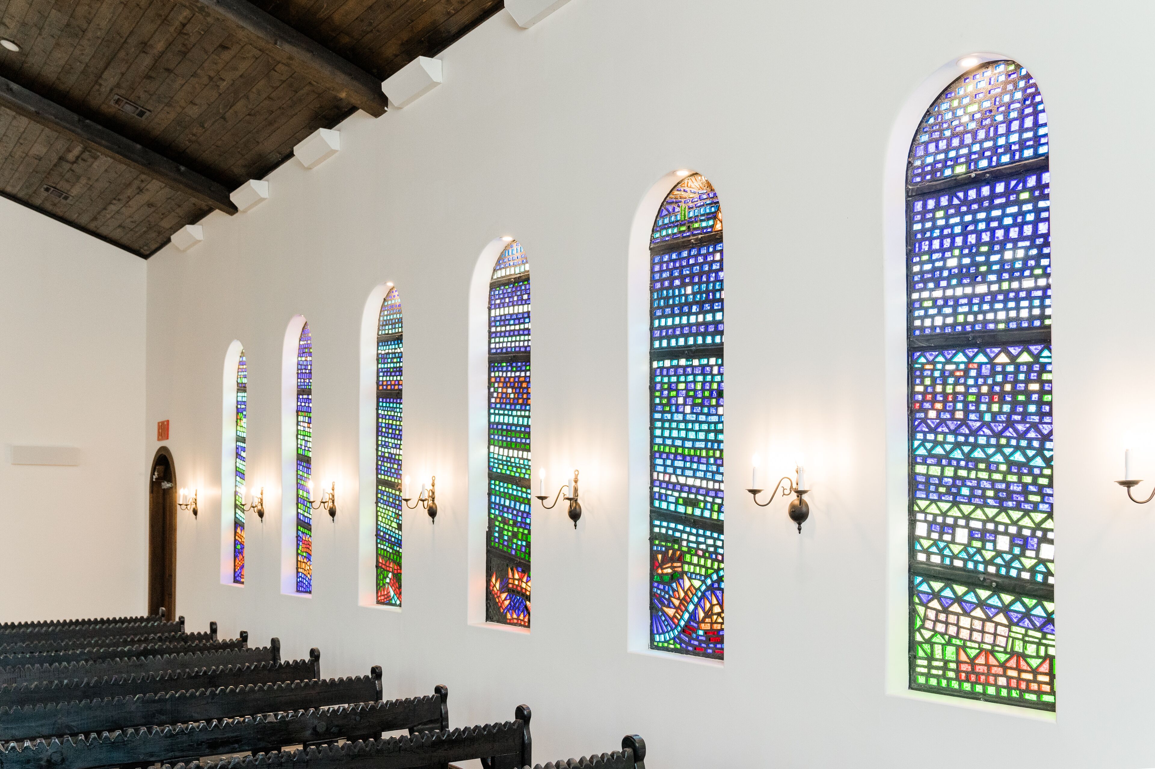 L'intérieur d'une église avec des vitraux et des bancs.