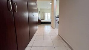 A hallway with a dark wooden wardrobe, a tiled floor, and a laundry area with a washing machine.