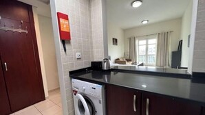 A modern kitchen with a built-in washing machine, a coffee maker, and a large window offering a view of the city.