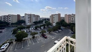 A residential area with multi-story apartment buildings, a parking lot, and a clear sky.