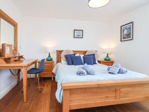 A neatly arranged bedroom with a wooden bed, a desk, and two bedside tables with lamps. - Navigators Rest (Whitby)