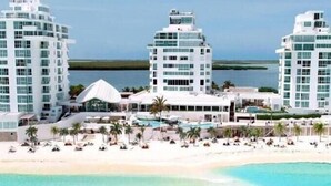 A beachfront hotel with multiple high-rise buildings, a pool area, and a sandy beach. - STUDIO 1 AT THE BEST BEACH IN CANCUN (Cancún)