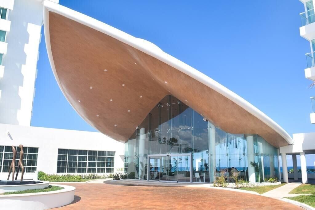 A modern building with a unique curved roof and large glass windows.