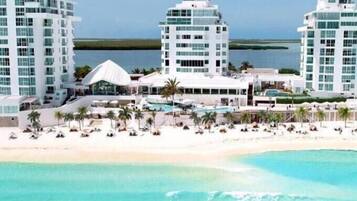 A beachfront hotel with multiple high-rise buildings, a pool area, and a sandy beach.