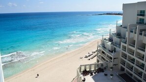A beach view from a hotel balcony with a pool and sun loungers. - breathtaking studio, w/ocean and lagoon views, amazing wrap around balcony,... (Cancún)