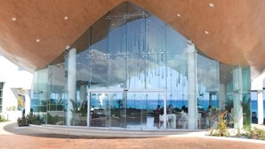 A modern building with a glass facade, large columns, and a view of the ocean. - breathtaking studio, w/ocean and lagoon views, amazing wrap around balcony,... (Cancún)