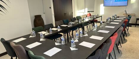 Un salón de conferencias con una larga mesa, sillas, botellas de agua y una pantalla de televisión mostrando "Kyriad DIRECT".