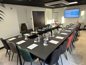 A conference room with a long table, chairs, water bottles, and a TV screen displaying "Kyriad DIRECT". - Kyriad Direct Orleans Nord - Cap Saran (Saran)