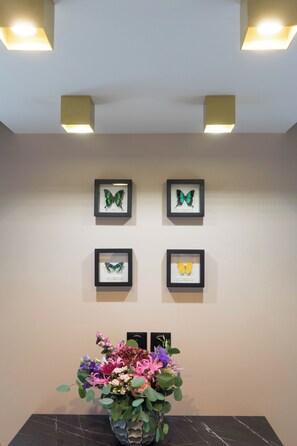 A wall with four framed butterfly pictures and a vase of flowers on a table. - Kyriad Direct Orleans Nord - Cap Saran (Saran)