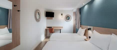 Habitación de hotel con dos camas, un escritorio, un televisor y un espejo.