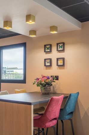 A dining area with a wooden table, two chairs, a vase with flowers, and butterfly wall art. - Kyriad Direct Orleans Nord - Cap Saran (Saran)