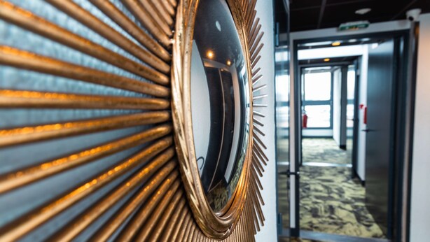 A hallway with a decorative mirror and a patterned carpet. - Kyriad Direct Orleans Nord - Cap Saran (Saran)