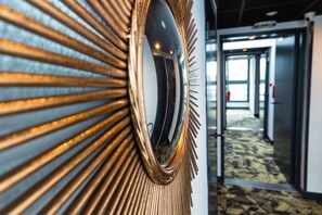 A hallway with a decorative mirror and a patterned carpet.