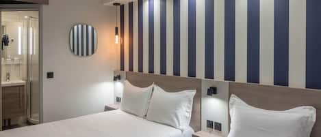 A hotel room with two beds, a large mirror, and a striped wall.