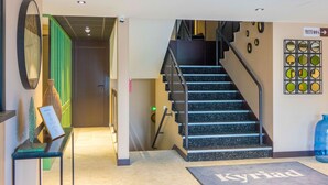A hotel lobby with a staircase, a reception desk, and a sign indicating the direction to the toilets. - Kyriad Direct Orleans Nord - Cap Saran (Saran)