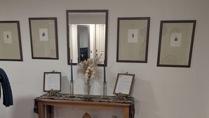 Ein Zimmer mit einem Holzkonsolentisch, gerahmten Bildern an der Wand, einem Spiegel und einer Vase mit Trockenblumen.